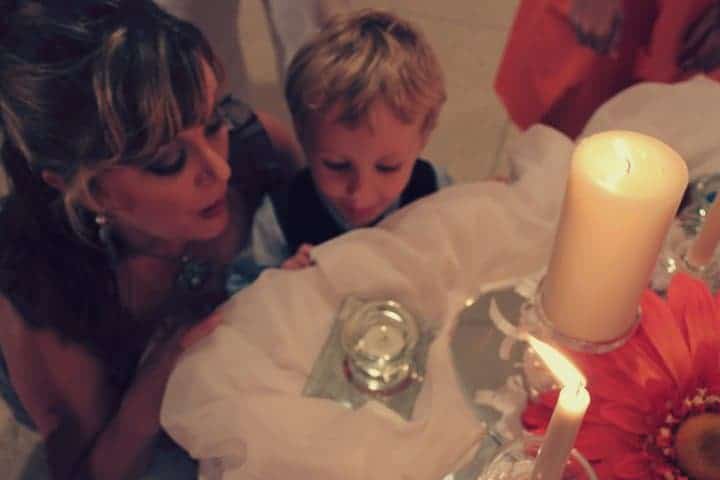 Jada and child blowing out a candle at a wedding.