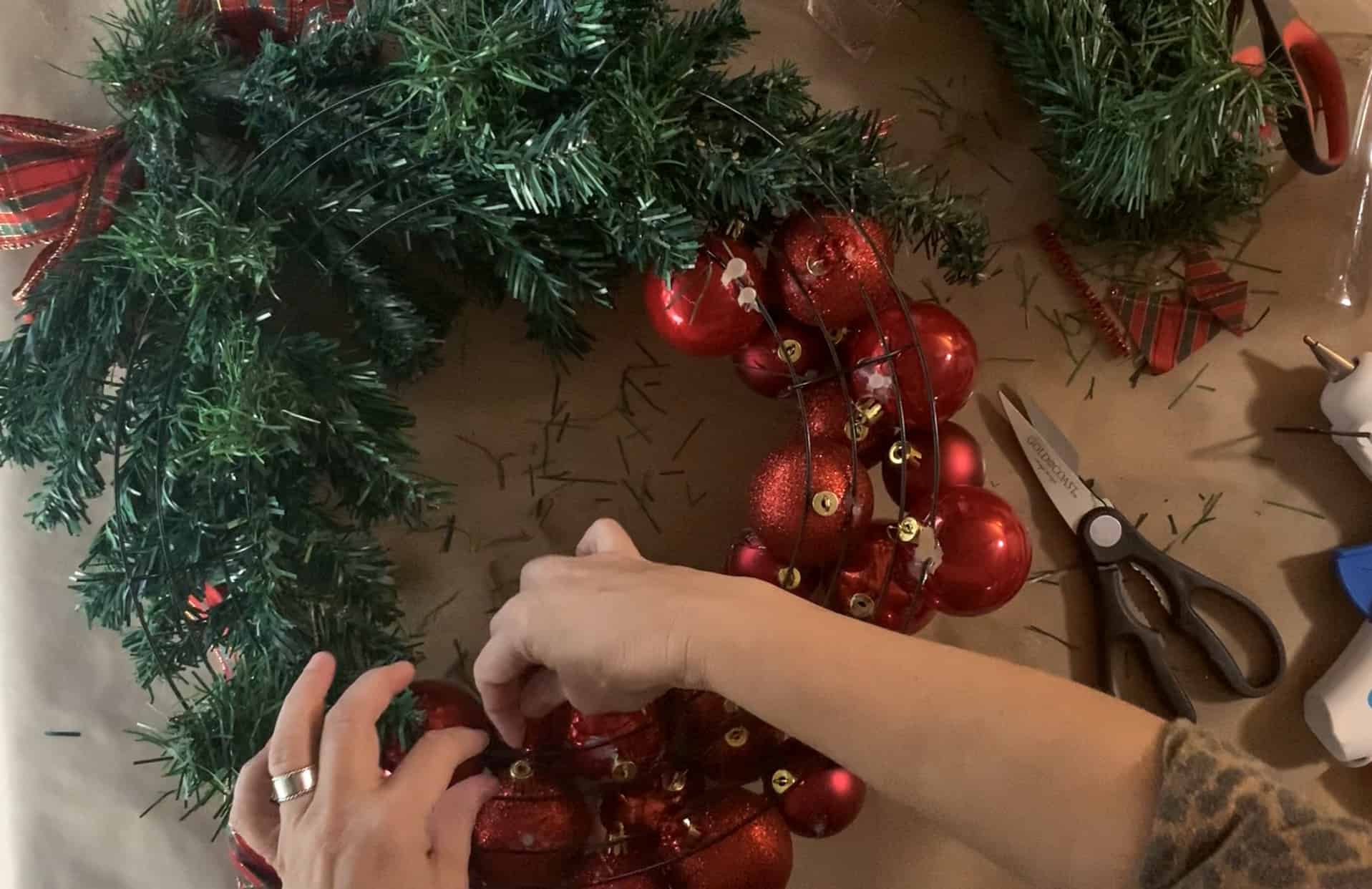 Using pipe cleaners to firmly secure ornaments to wire wreath form.