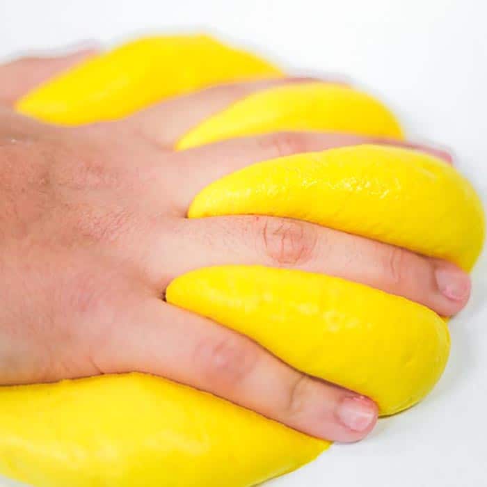 Close up of child's hand squished into butter slime.