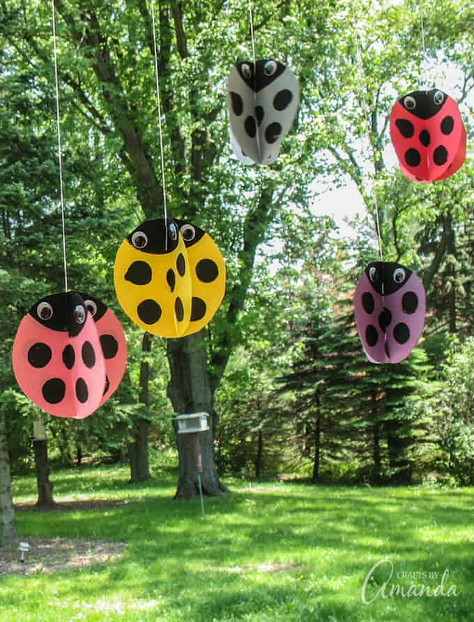 Twirling ladybug crafts hanging from a tree.