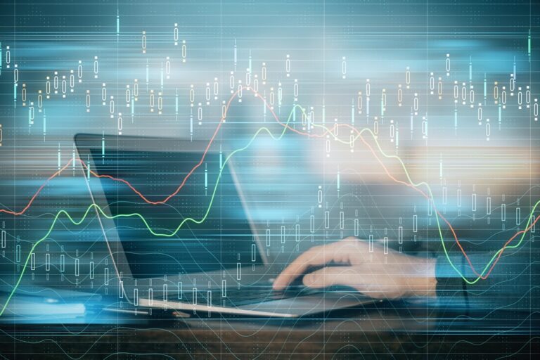 A person types on a laptop with transparent graphs and financial data overlays, symbolizing data analysis, stock market trends, or financial trading in a digital environment.