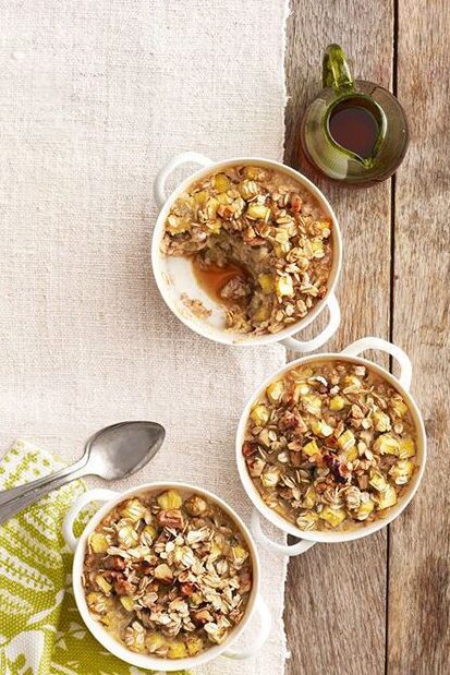 A person wearing a light blue shirt and jeans sits with one hand resting on their chin and the other holding a white mug, looking relaxed in a bright, minimalistic room.