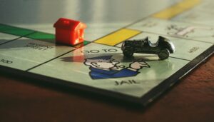 Close-up shot of a Monopoly board game featuring a toy car and a red house on 'Go to Jail'.