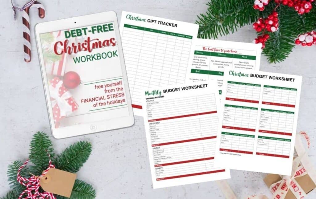 A flat lay image showing a tablet displaying a Debt-Free Christmas Workbook cover and printed holiday budgeting worksheets, surrounded by festive decorations, candy cane, evergreen branches, and ribbon-wrapped gifts.