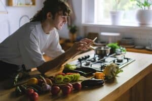 A young chef captures fresh vegetables on a kitchen counter for a blog post.