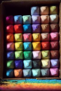 A colorful array of square pastels arranged neatly in a box, perfect for art projects.