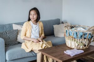 A teenage girl folding laundry while seated on a couch, emphasizing home chores.