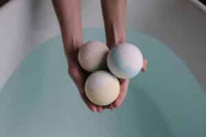 A soothing image of three bath bombs held over a tranquil bath, ideal for relaxation themes.