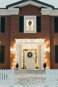 Charming brick house with festive Christmas wreath and lights, perfect for holiday atmosphere.