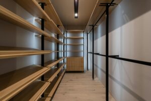 Explore a spacious modern walk-in closet with wooden shelves and sleek design, perfect for organizing.