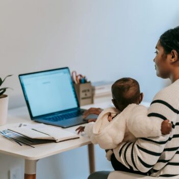 mother carrying her baby while working from home