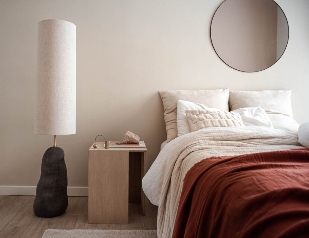 A neutral bedroom with a rust colored throw on the bed