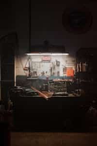 A moody, dimly lit workshop with neatly arranged tools and equipment, evoking a sense of craft and diligence.